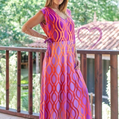 Mulher a usar macacão rosa e laranja com padrão geométrico, em varanda exterior