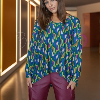 Pessoa com blusa colorida e calças largas vinho em corredor iluminado