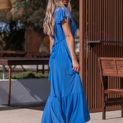 Mulher de vestido azul midi com faixa na cintura e sandálias bege ao ar livre