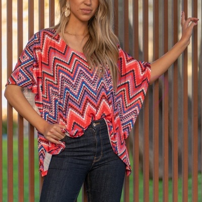 Blusa feminina colorida com padrão zig-zag e jeans escuro em ambiente exterior