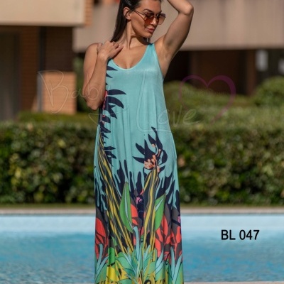 Vestido longo azul claro com padrão colorido de folhas e flores, usado por mulher junto a piscina