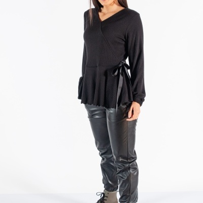 Mulher com camisola preta, calças de pele sintética pretas e botas cinzentas