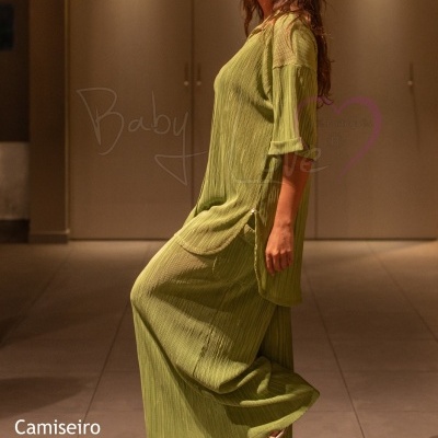 Mulher com conjunto verde claro de tecido texturizado e sandálias de salto em ambiente interior iluminado