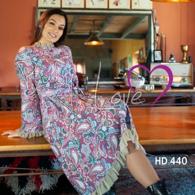 Vestido comprido com padrão paisley e botas pretas em ambiente interior acolhedor