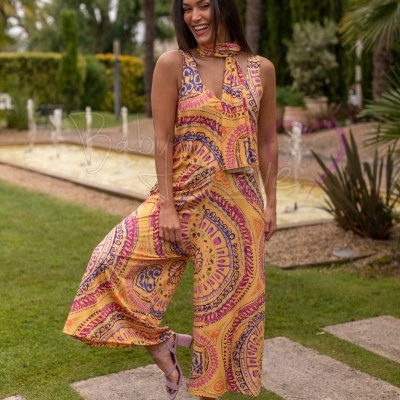 Conjunto feminino cor de rosa e amarelo com padrão circular usado num jardim