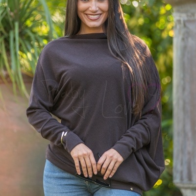 Mulher com camisola castanha de malha fina e jeans azul claro em ambiente exterior