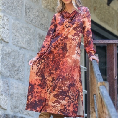 Vestido comprido com padrão em laranja e castanho com botas castanhas na escada