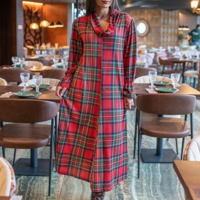 Vestido comprido vermelho xadrez com gola caída e botas castanhas num restaurante