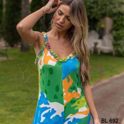 Vestido longo colorido com padrão abstrato e alças finas num jardim