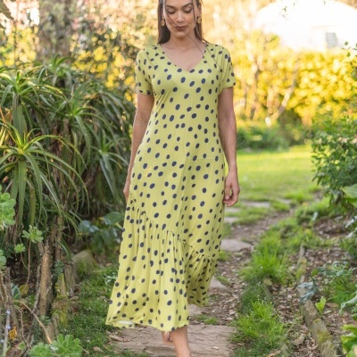 Vestido amarelo com bolinhas pretas e decote em V visto em modelo feminina ao ar livre