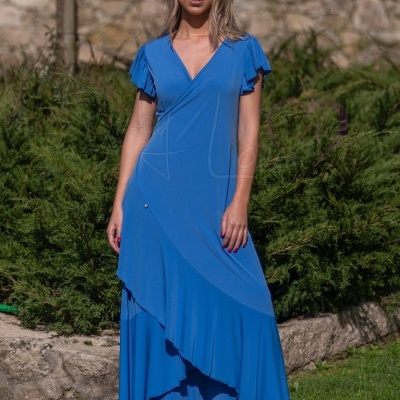 Vestido azul com decote em V e folhos nas mangas, usado ao ar livre junto a muro de pedra.