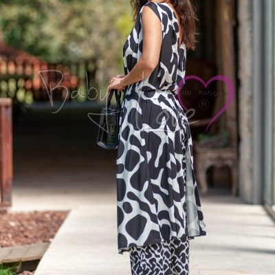 Modelo de mulher a usar conjunto preto e branco abstrato com vestido e calças, bolsa preta e óculos escuros