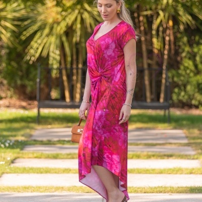 Vestido rosa e vermelho padrão floral com nó frontal, corte assimétrico, sandálias e mala castanha em parque