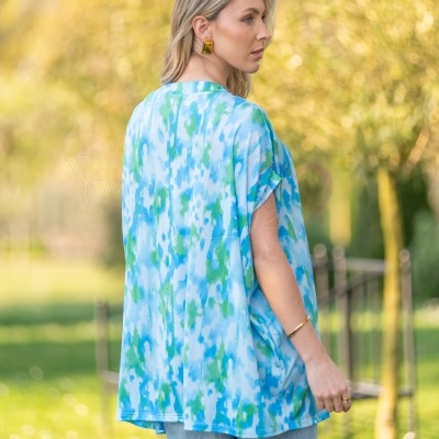 Top feminino tie-dye azul e verde com calças de ganga e acessórios dourados