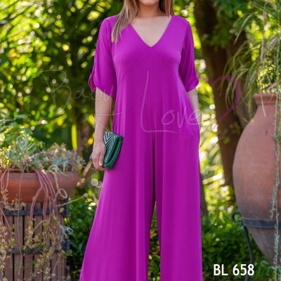 Macacão rosa pink de manga 3/4 com decote em V e calças largas, mulher com carteira verde em ambiente exterior