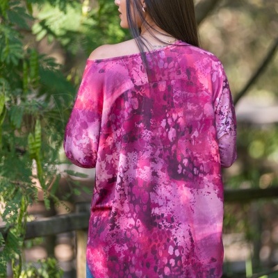 Túnica rosa com padrão abstrato em vários tons de rosa e roxo com decote assimétrico vista de costas