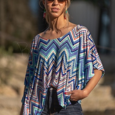 Blusa larga com padrão geométrico azul e calças jeans escuras