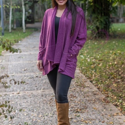 Mulher com cardigã roxo, leggings pretas e botas castanhas em caminho de pedra