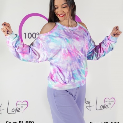 Mulher com sweat tie-dye lilás, azul e branco e calças lilás num fundo branco com texto Baby Love.