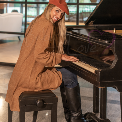 Mulher a tocar piano de cauda com casaco castanho e boina