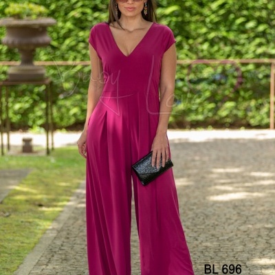 Mulher de macacão fúcsia com carteira preta e óculos de sol ao ar livre