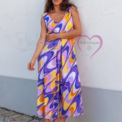 Macacão feminino colorido com padrão abstrato e decote em V junto a parede branca