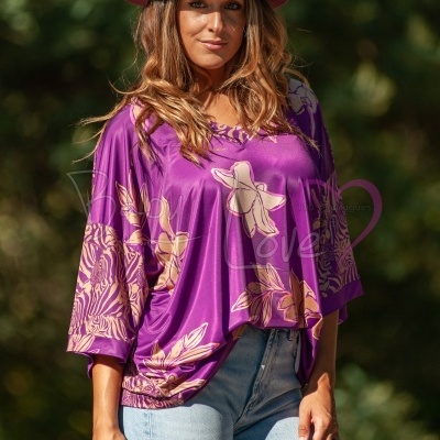 Mulher com blusa roxa floral e chapéu bordeaux em ambiente exterior