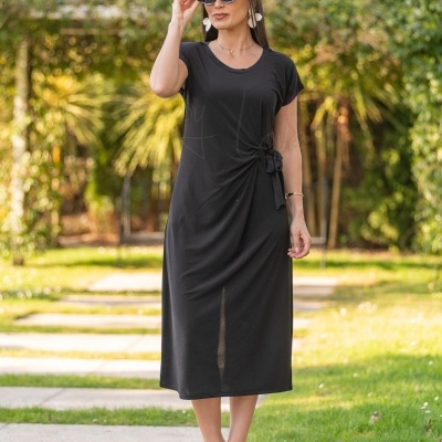 Vestido preto com nó na cintura usado por mulher com óculos escuros em jardim