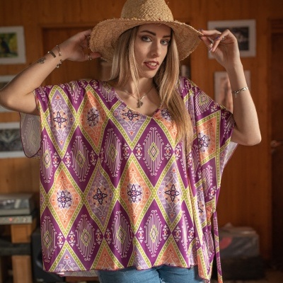 Mulher com blusa estampada colorida, chapéu de palha e calções de ganga em interior