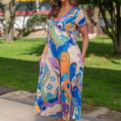 Vestido midi feminino com padrão colorido abstrato, decote em V e mangas curtas, em ambiente exterior com relvado