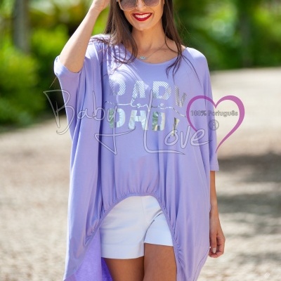 Mulher com túnica lilás e calções brancos ao ar livre