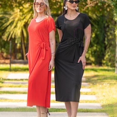 Duas mulheres com vestidos compridos vermelho e preto com nós laterais, óculos de sol e brincos, ao ar livre num jardim.