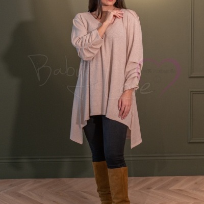 Mulher com túnica bege, calças pretas e botas castanhas em ambiente interior