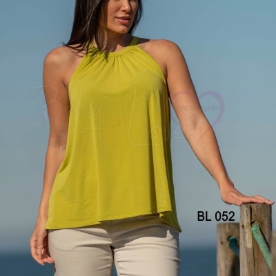 Mulher com top amarelo claro e calças claras junto ao mar