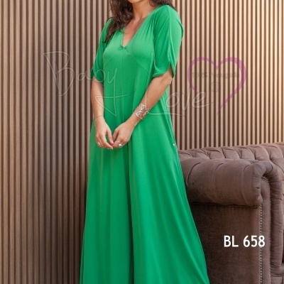 Macacão verde de manga curta com decote em V usado por mulher junto a sofá castanho