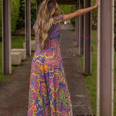 Vestido comprido colorido com padrão vibrante usado por mulher em passadiço exterior