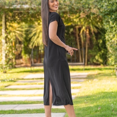 Mulher de vestido preto e salto transparente em jardim