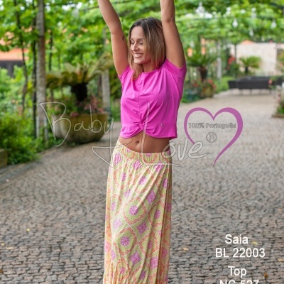 Mulher com saia comprida estampada e top rosa em rua de calçada portuguesa