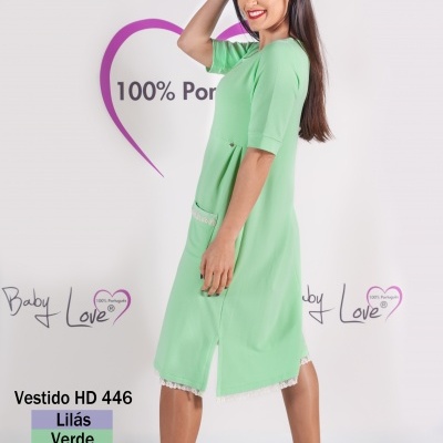 Vestido verde com rendas e sapatilhas brancas, modelo sorridente em fundo branco com texto Baby Love