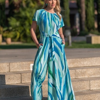 Macacão feminino azul e verde com faixa na cintura, modelo ao ar livre em escadaria.
