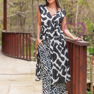 Macacão preto e branco com padrão animal usado por mulher com chapéu preto em varanda de madeira