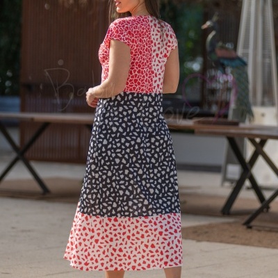 Vestido comprido com padrão bicolor em três blocos, vermelho, preto e branco, tecido leve, usado ao ar livre.