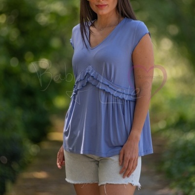 Mulher com blusa azul e calções de ganga num ambiente exterior