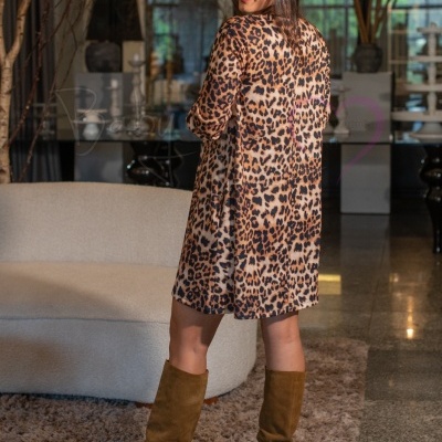 Mulher de vestido animal print e botas castanhas em sala moderna