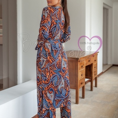 Conjunto de kimono e calças com padrão abstrato em tons de laranja, azul e castanho, em ambiente interior