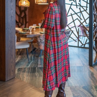 Vestido comprido xadrez vermelho e botas castanhas em ambiente interior
