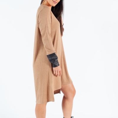 Mulher de perfil vestindo vestido de malha castanho claro com punhos pretos e botas pretas