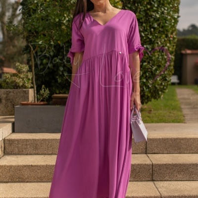 Mulher com vestido rosa comprido e sandálias roxas em escadas ao ar livre