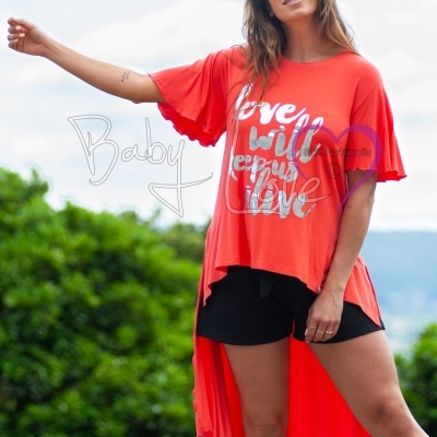 Mulher com t-shirt coral de cauda longa e calções pretos ao ar livre