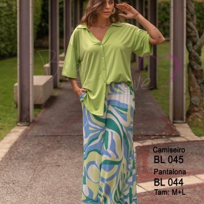 Mulher com camisa verde claro e calças largas coloridas em passadiço externo